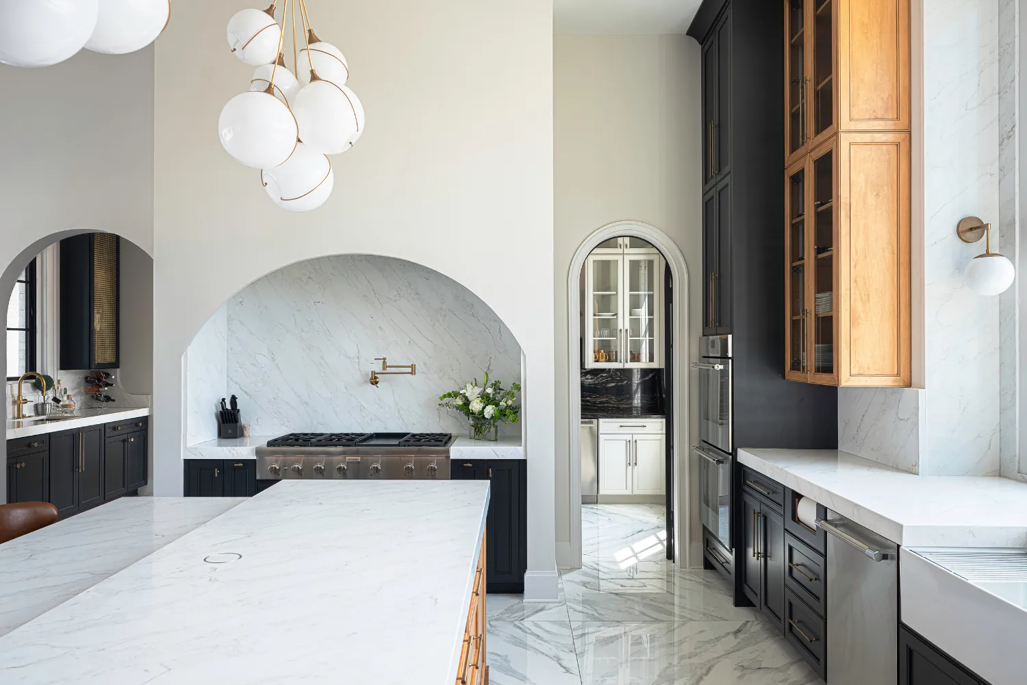 Williamson Residence kitchen with arched plaster range hood and marble finishes