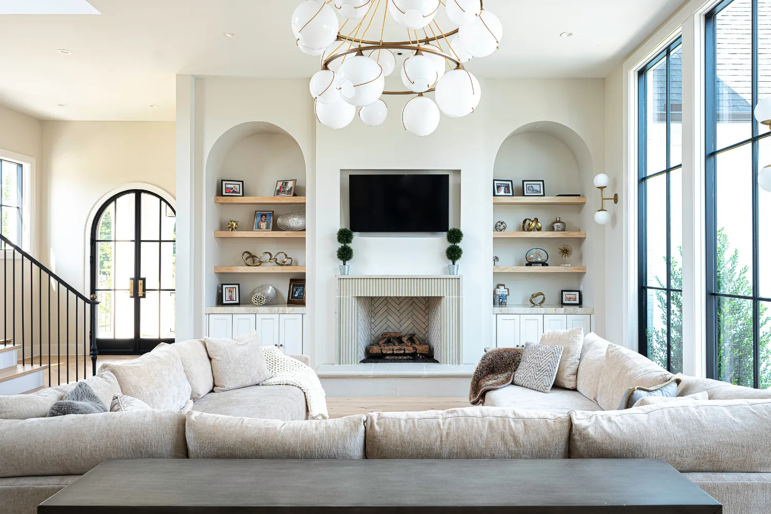 Bright Williamson Residence living room with fireplace, arched built-in shelves and tall windows