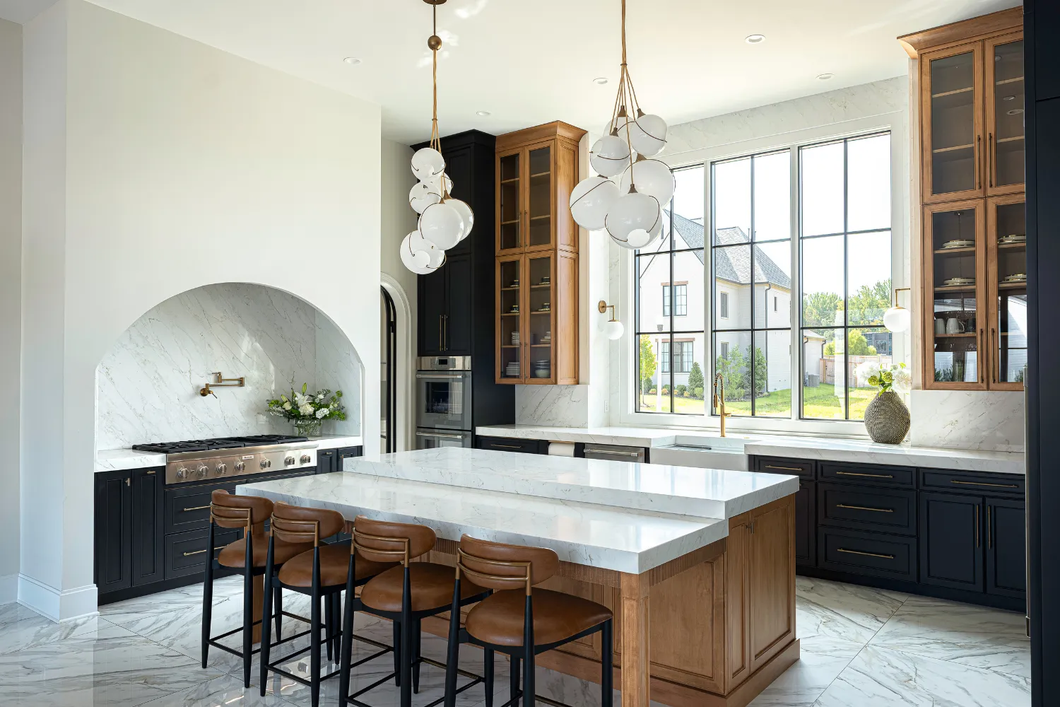 Williamson Residence kitchen with marble island, brass fixtures and dark wood storage